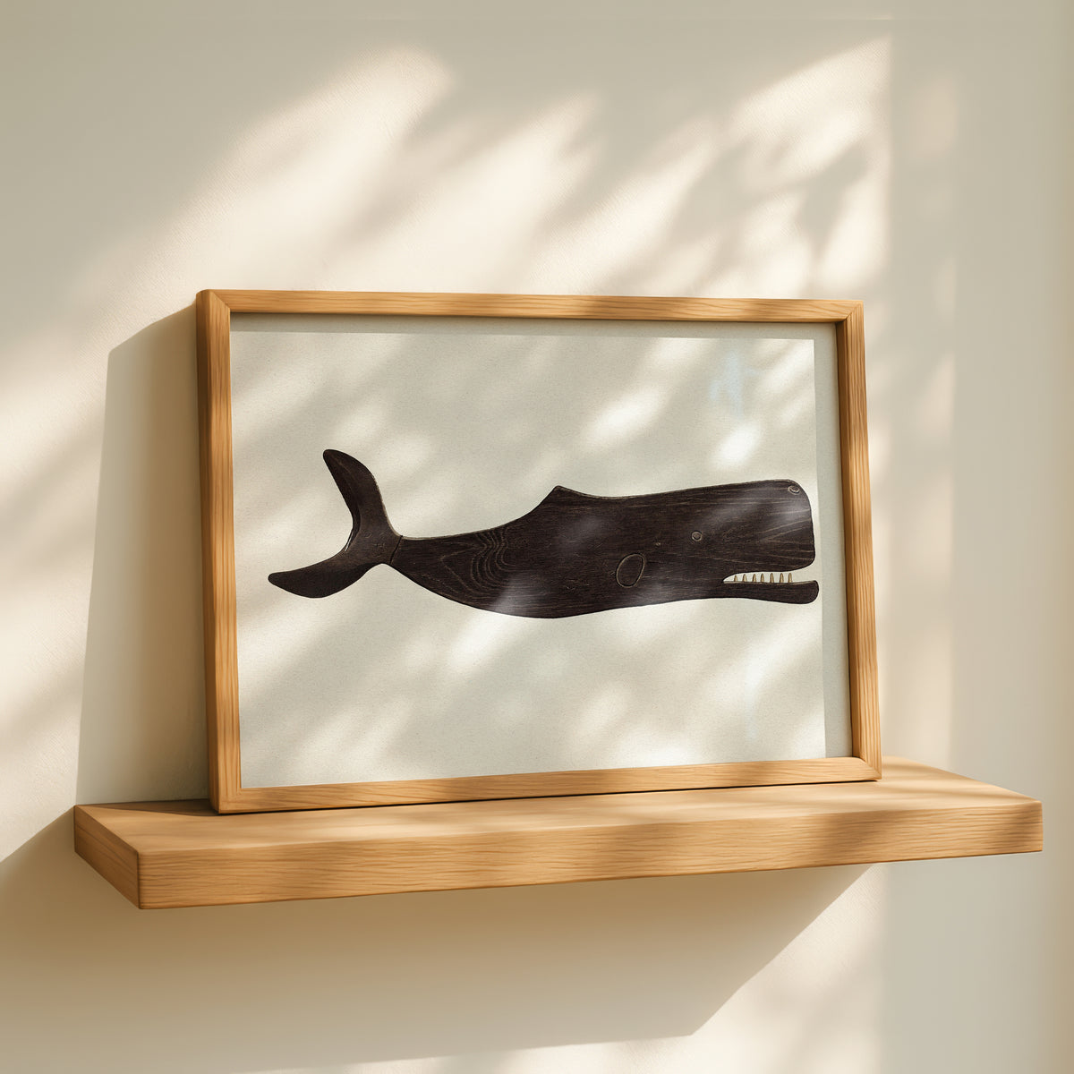Framed artwork of a whale on a wooden shelf with sunlight casting shadows.
