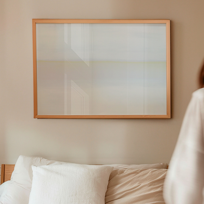 Minimal neutral seascape print in soft white and beige tones above a bed in a calm bedroom