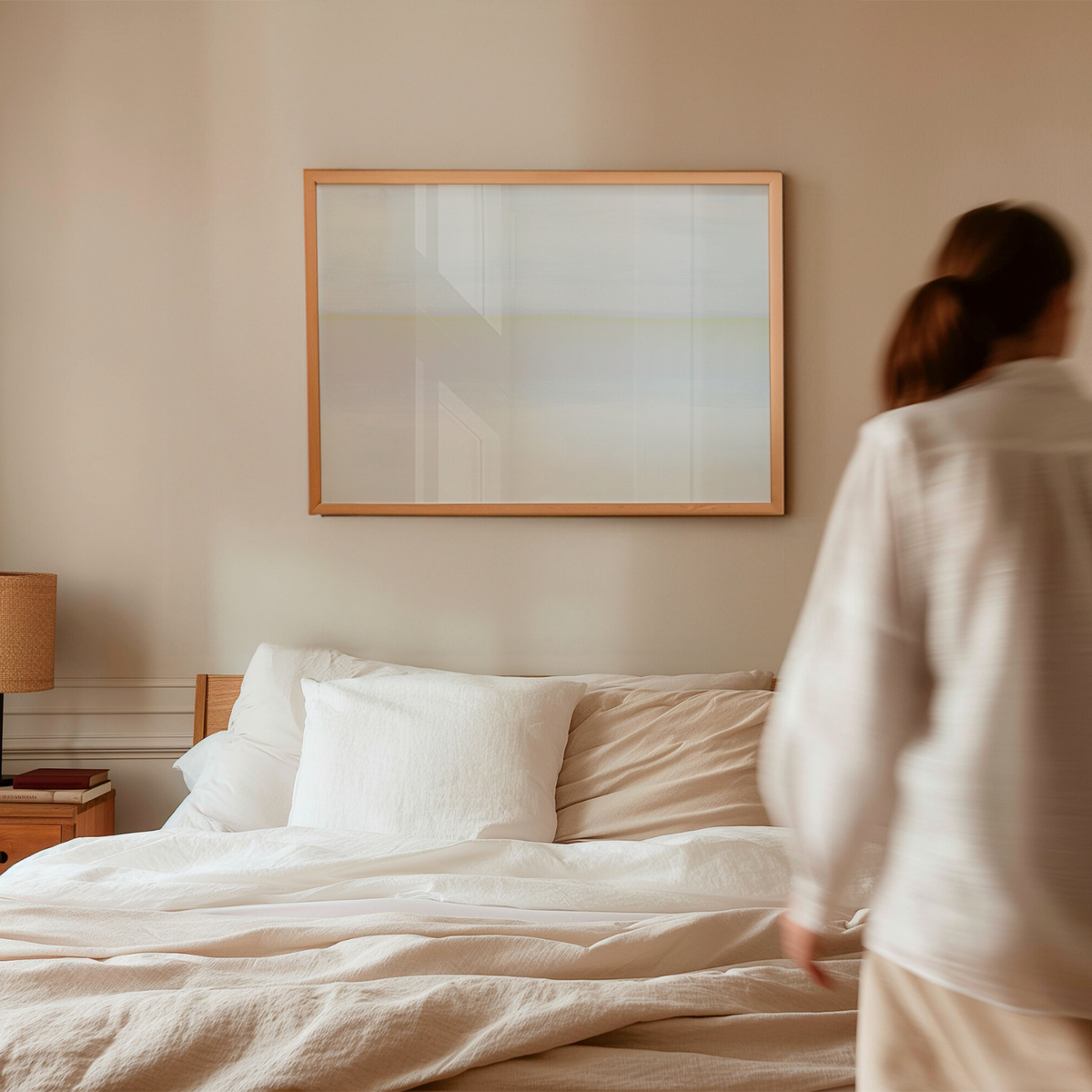 Framed minimal coastal wall art with soft horizon line in neutral tones in a light bedroom interior