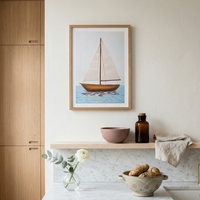 Framed sailboat artwork on a wall above a kitchen counter with various items.