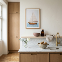 Modern kitchen with wooden cabinets, marble countertop, and sailboat artwork on the wall.