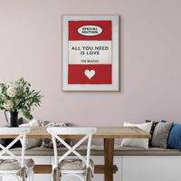 Vintage red book cover with All You Need is Love as the title by the Beatles hanging on a pink wall above a white sideboard- Beach House Art