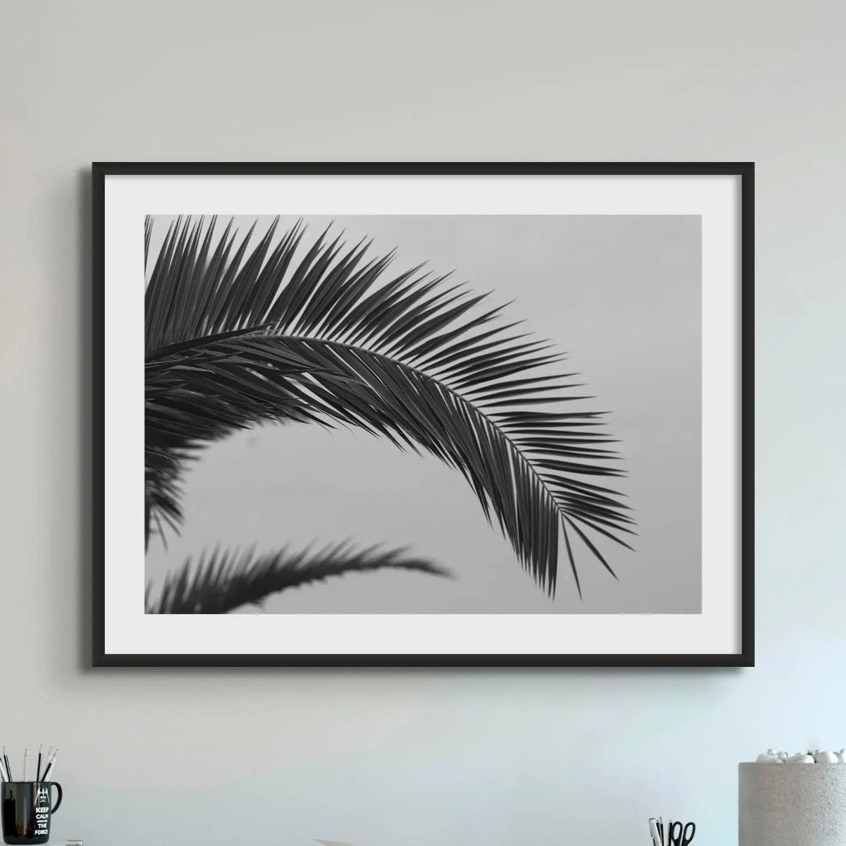 black and white beach art photograph of a palm tree frond in a black frame above a console table - beach house art