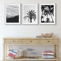 set of three black and white beach art photographs in natural frames above a weathered timber side board - beach house art
