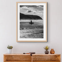 black & white beach art photograph of a solitary surfer walking into the waves framed above a small desk - beach house art